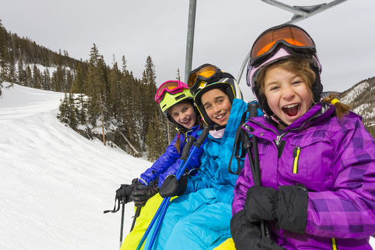 Girls riding ski lift on snowy slope
