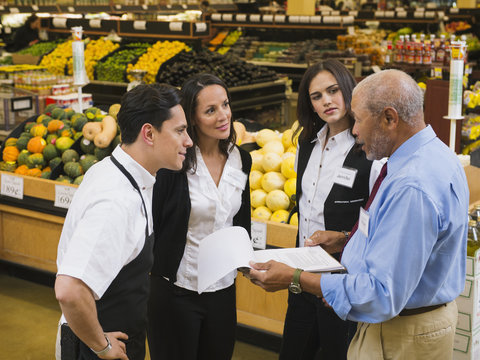 Businessman and workers talking in grocery store