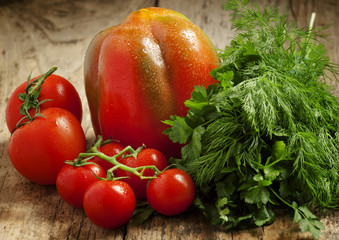 Fresh red tomatoes with parsley and dill on a wooden table