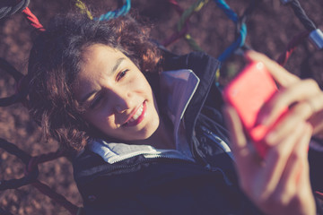 Fototapeta na wymiar Young girl texting/using phone while sitting on hammock