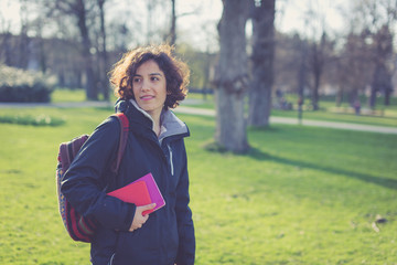 Young student holding books and walking around campus