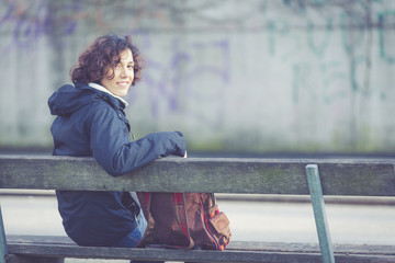 Young student sitting on a bench at park/campus