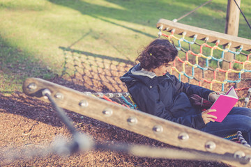 Young girl reading in a hammock