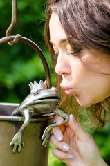 Young woman kissing a frog