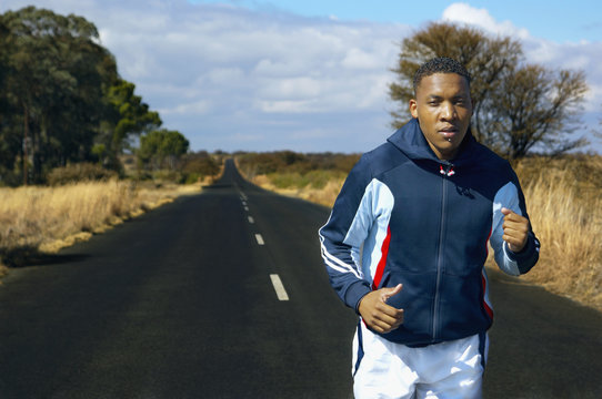 Mixed Race Man Running On Remote Road