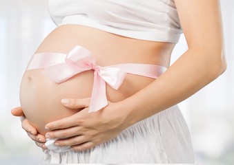 Fototapeta na wymiar Abdomen. Pregnant belly with pink ribbon