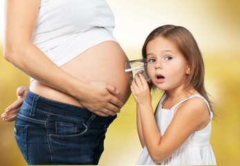 Pregnant. Kid girl listening with can pregnant mother's stomach