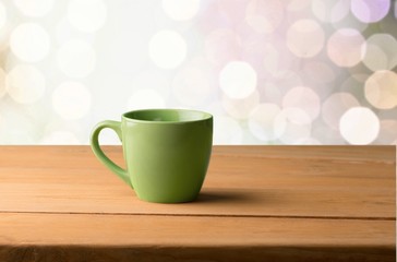 Backdrop. Green mug on wooden table over grunge background