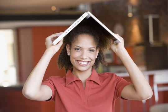 African woman holding laptop on head