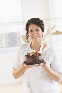 Hispanic baker holding chocolate cake