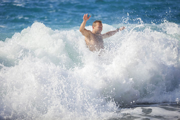 Young man bathing in storming sea, water in focus