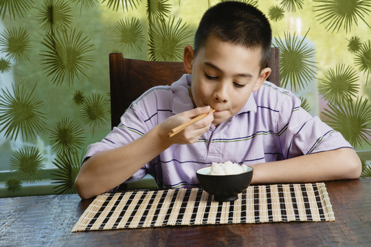 Asian boy eating bowl of rice