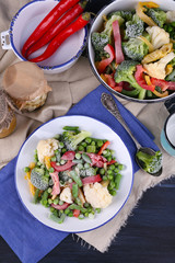 Frozen vegetables on plate on napkin, on wooden table background