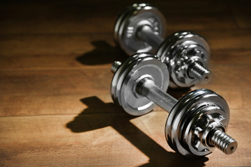 Dumbbells on wooden floor, on dark background