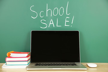 Laptop on table, on green blackboard background