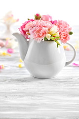 Beautiful spring flowers in teapot on wooden table, closeup