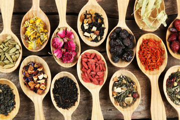 Collection of tea and natural additives in wooden spoons, on old wooden table - obrazy, fototapety, plakaty