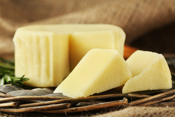 Cheese on wicker tray and sackcloth, closeup