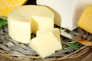 Different sort of cheese on wicker tray, closeup