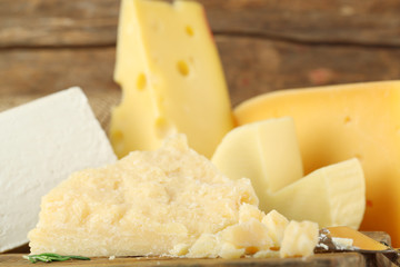 Different sort of cheese on wooden cutting board, closeup