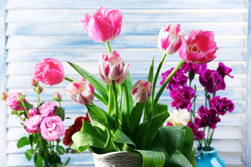 Different beautiful flowers in vases on wooden background