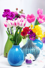 Beautiful composition with different flowers in vases on wall background