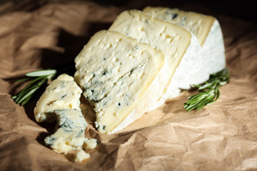 Pieces of tasty blue cheese with rosemary on paper background