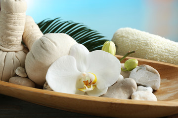 Still life with beautiful blooming orchid flower, spa treatment in bowl, on wooden table, on bright background