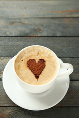 Cup of cappuccino with heart of cocoa on wooden table