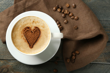 Cup of cappuccino with heart of cocoa on wooden table
