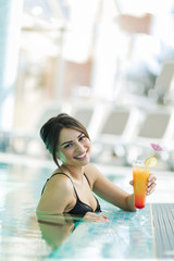 Beautiful lady drinking a cocktail in a swimming pool and relaxi
