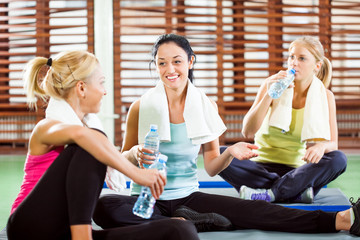 Happy women relaxing and talking after fitness training