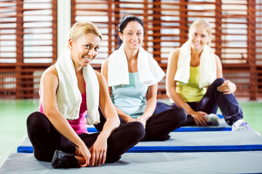 Happy women in gym with fitness instructor before training
