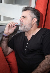 Fototapeta na wymiar Attractive Senior with white beard smoking electronic cigarette