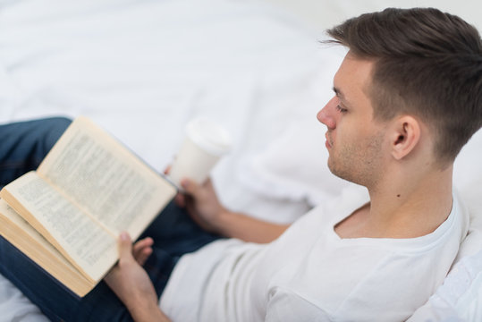 Man reading a book on his bed at home