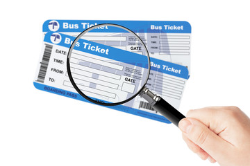 Bus boarding pass tickets with magnifier glass in hand