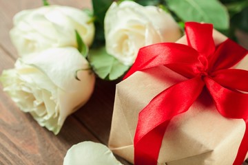 Day. Red roses and holiday gift on a wooden table