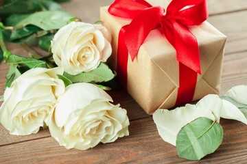 Fototapeta premium Day. Red roses and holiday gift on a wooden table
