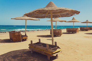 Deserted beach with wattled sun umbrellas on a seashore.
