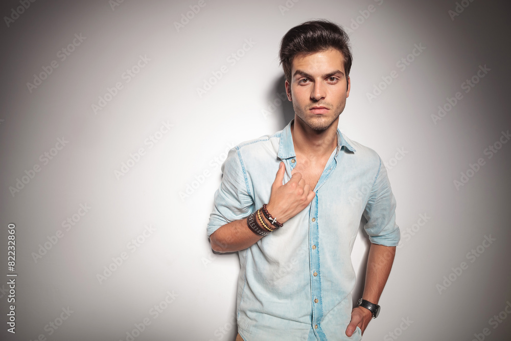 Poster Cool young fashion man leaning on studio background