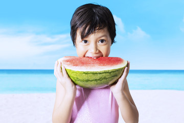 Kid eats watermelon on the beach