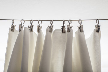 cream-colored curtain hanging on a string on metal hooks
