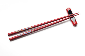 Red wooden chopsticks and chopstick rest on white background
