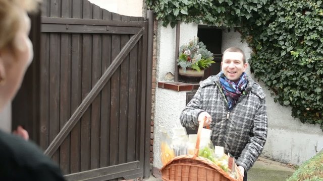 Seller carries product of pasta (in basket) to customer in home