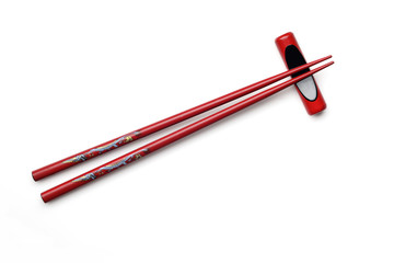 Red wooden chopsticks and chopstick rest on white background