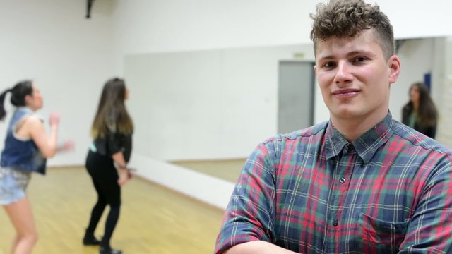 man smiles to camera - two woman dancing