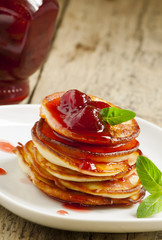 Hot pancakes with strawberry jam and mint leaves, selective focu