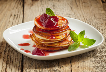 Hot pancakes with strawberry jam and mint leaves, selective focu