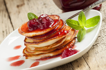 Hot pancakes with strawberry jam and mint leaves, selective focu