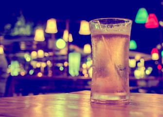 Glass of beer with bar scene in the background
